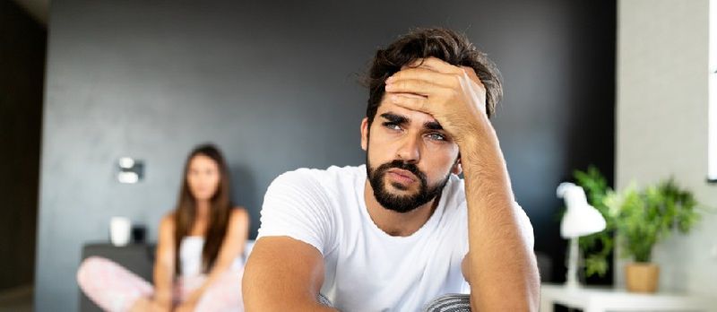 מענטש זיצן אין בעט און טראכטן בשעת פרוי זיצט הינטער אים