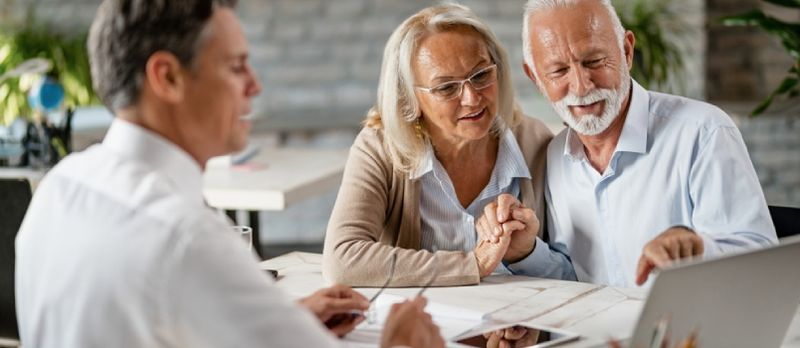 Heureux couple de personnes âgées se tenant la main et utilisant un ordinateur portable lors d