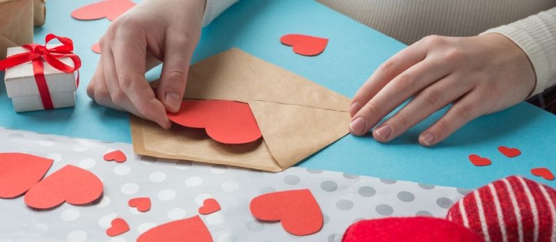 Les mains de la fille préparent un cadeau pour la Saint-Valentin