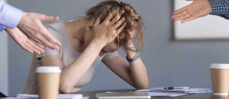 Stressato giovane imprenditrice tenendo la testa nelle mani che soffrono di discriminazione sleale di genere sul lavoro concetto, dipendente donna frustrata da colleghi maschi bullismo donna umiliante sul posto di lavoro