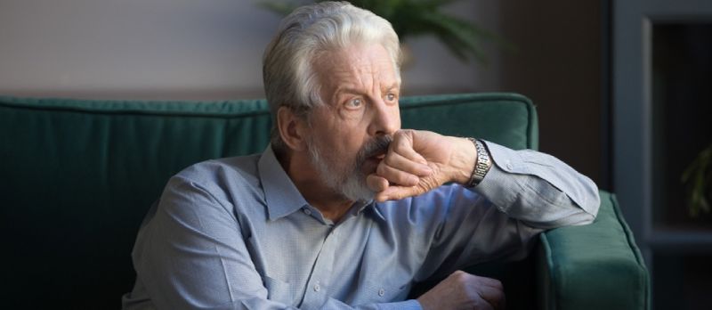 Alen eelere Mann, deen eleng op de Canapé Doheem sëtzt, denkt un traureg Gedanken verluer