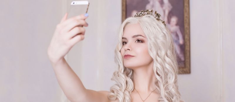 Una chica glamorosa, una mujer rubia con una corona, hace un selfie