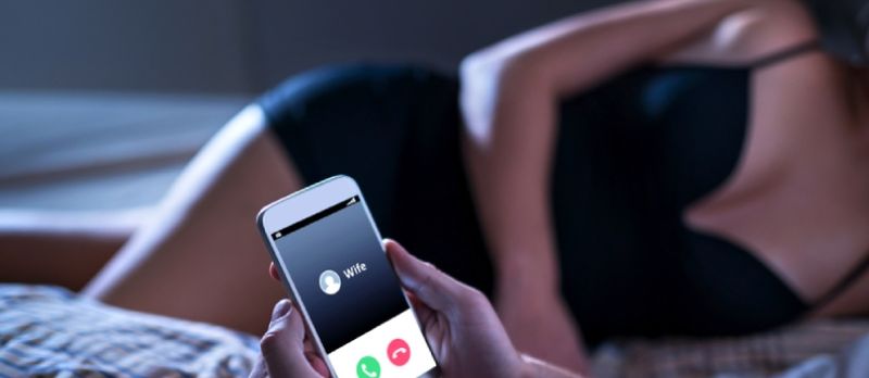 Mashtruesi i pabesë i shtrirë me zonjën në shtratin e hotelit. Thirrje nga gruaja në celular