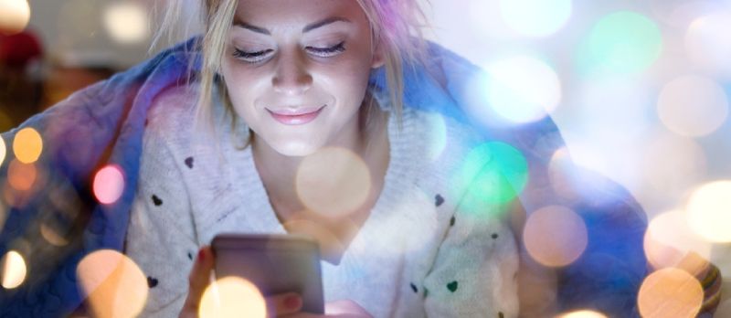 qadın gülümsəyərək telefonuna baxır
