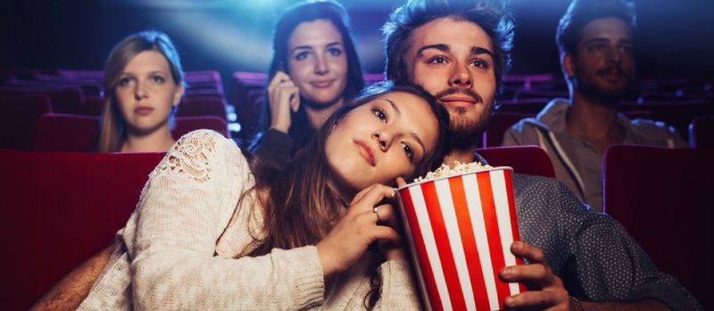 Paartjie kyk fliek of vertoning in teater met springmieliesboks