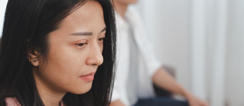 Las parejas asiáticas jóvenes infelices pelean en el sofá, las relaciones están en problemas