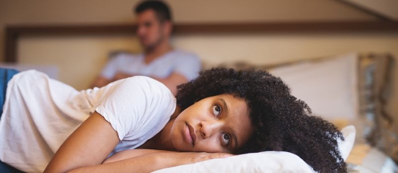Traureg Fra déi um Bett leien no engem Sträit mat hirem Frënd.