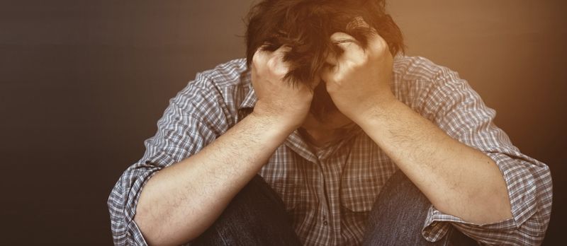 Traurege depriméierte Mann hält Kapp mat Hand mat isoléierten Hannergrondstudio