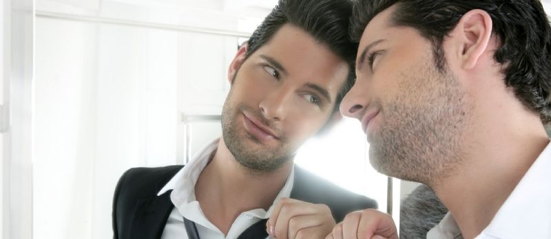 Vestito narcisistico bello Giovane orgoglioso che si guarda allo specchio