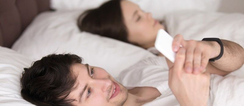 Mann am Telefon beschäftigt, während Frau schläft