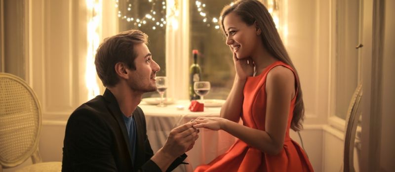 Kjekk mann foreslår at en vakker kvinne skal gifte seg med ham i en elegant restaurant