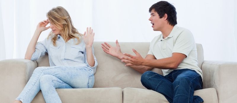 E Mann, deen op enger Couch sëtzt, huet e Sträit mat senger Frëndin, déi hire Kapp ewechgedréint huet