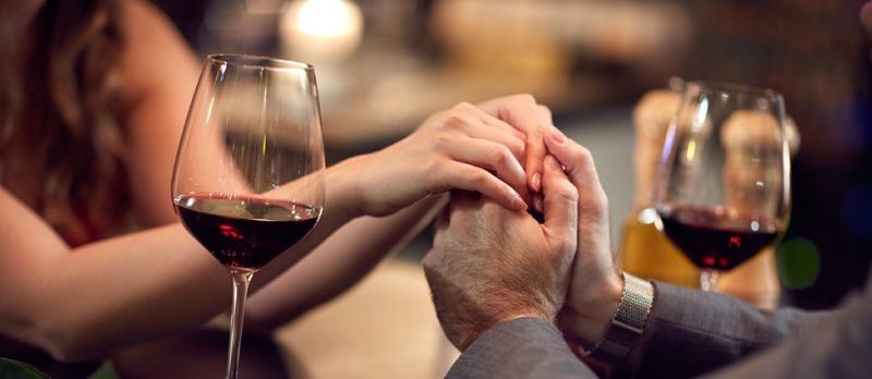 Pareja amorosa saliendo con dos copas de vino y sosteniendo sus manos juntas Primer plano