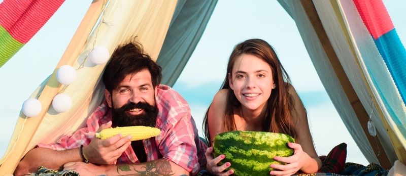 Amateurs de camping. Couple romantique mangeant de la pastèque et du maïs.