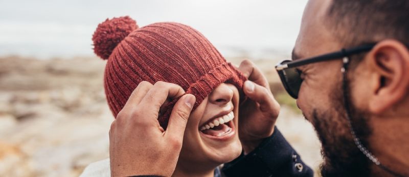 پيار ڪندڙ جوڙو ٻاهر تفريح ڪندي. مرد عورت جون اکيون ٽوپي سان ڍڪيندي