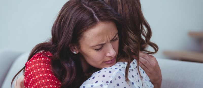 Femme déprimée embrassant son amie à la maison