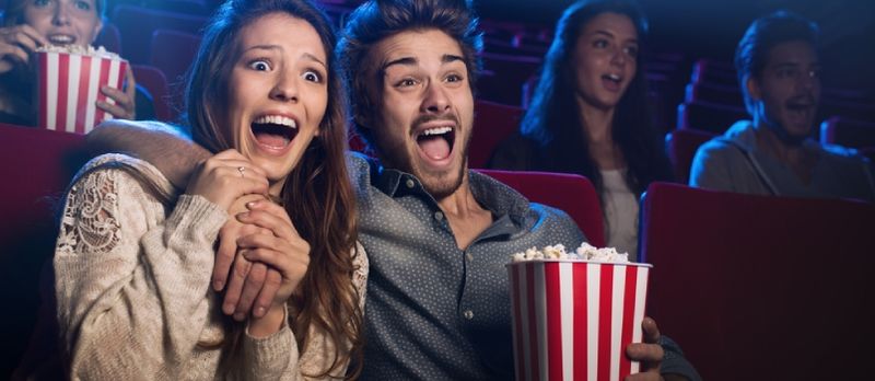 Mladi uplašeni par u kinu gleda horor film i vrišti, ona drži svog dečka
