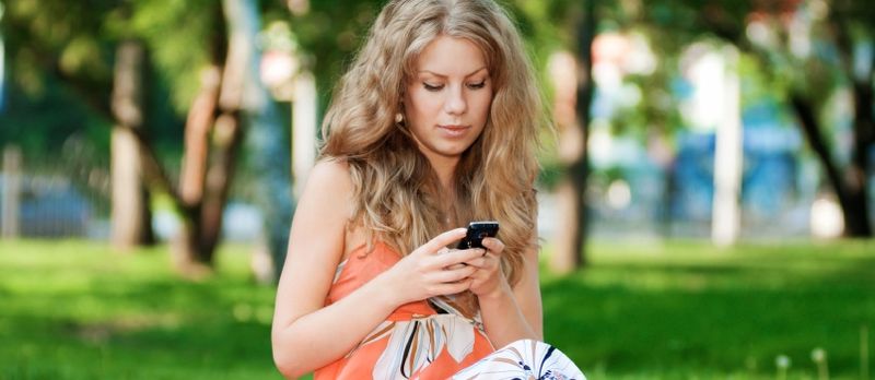 Gənc xoşbəxt qadın mobil telefonla mesajlaşır