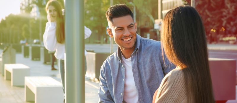 Mujer joven espiando a su novio al aire libre. Concepto de engaño