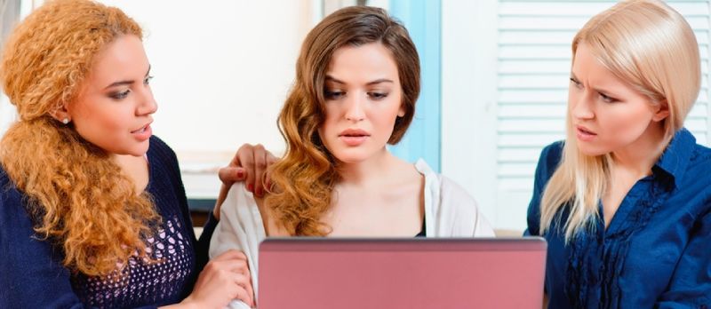 νεαρή γυναίκα κοιτάζοντας το φορητό υπολογιστή της ενώ οι καλύτερες φίλες της την παρηγορούν