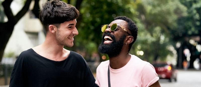 Càraid gay ioma-ghnèitheach fìor, Afro Ameireaganach agus fear geal a’ gàireachdainn, gàire mòr ann an gaol.