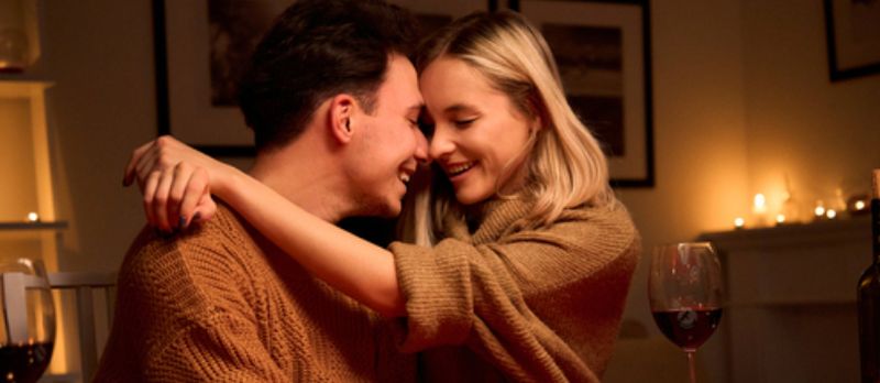 Pareja teniendo romance junto con la decoración romántica de la noche de velas