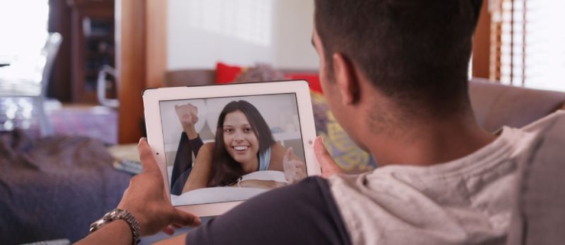 Hombre milenario chateando por video o teniendo una conversación en Facetime con su novia en una tableta