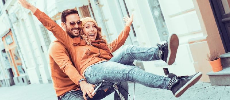 Pareja joven divirtiéndose en la ciudad. Pareja joven feliz yendo a dar un paseo en bicicleta en un día de otoño en la ciudad.