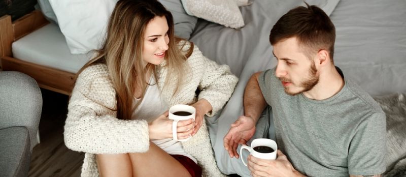 Par med kaffe sitter på gulvet og snakker