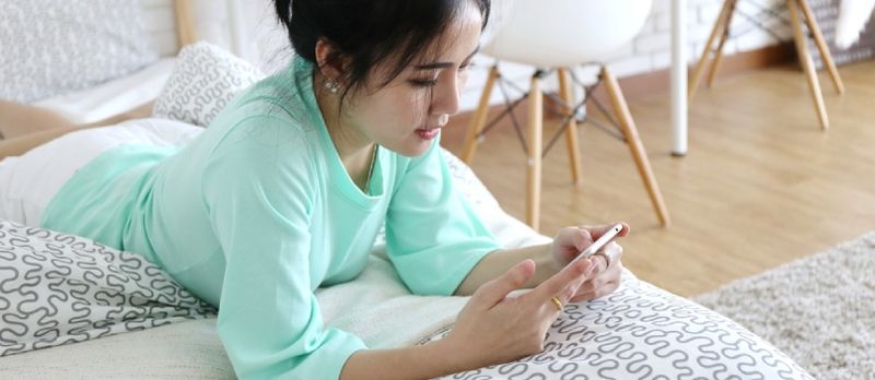 Charmante belle peau bronzée femme asiatique main utiliser téléphone allongé sur le lit