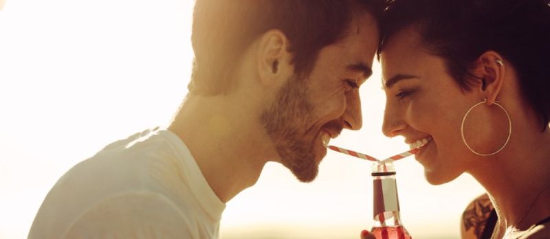 Homem e mulher bebendo romanticamente da mesma garrafa