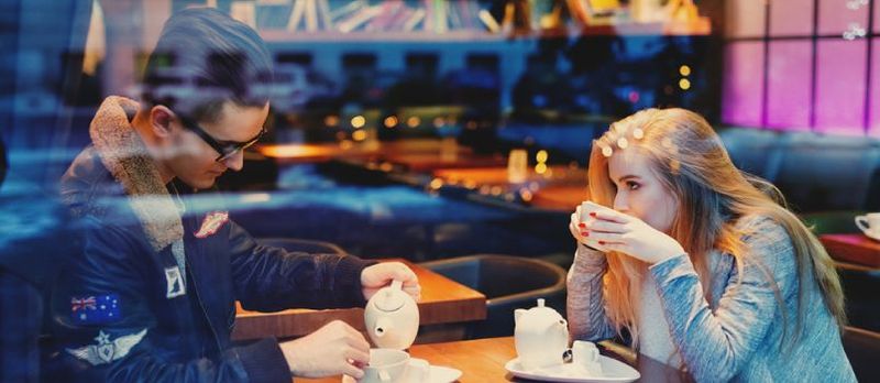 Homem e mulher sentados em uma mesa tomando café juntos em um encontro