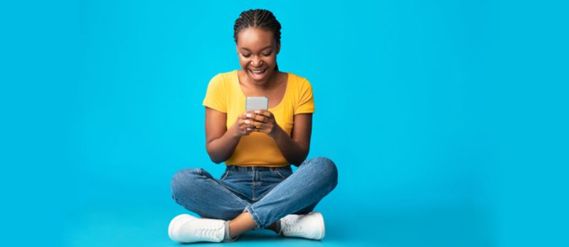 Portret kobiety korzystającej z telefonu komórkowego z odosobnionym tłem ściany studyjnej