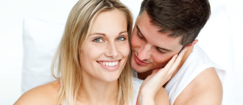 Hombre atractivo abrazando a su hermosa novia en la cama