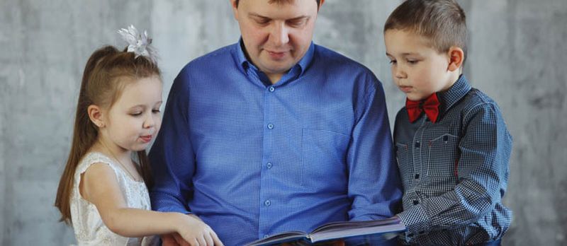 Jonke Papp an engem bloen Hiem Liest e Buch fir säi Jong an d